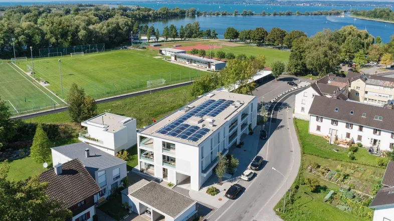 Moderne Wohnanlage mit Solaranlage und Blick auf den See und Sportplätze.