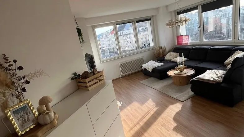 Helles Wohnzimmer mit großem Sofa, Holzfußboden und weitem Blick durch die Fenster.