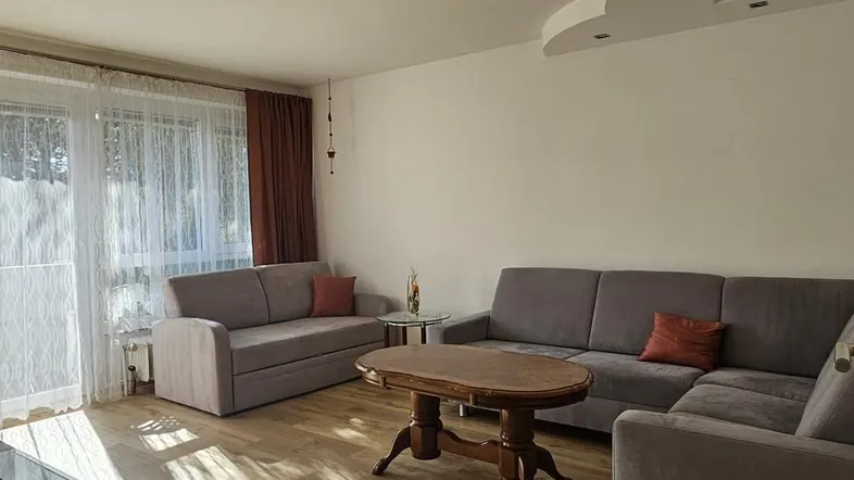 Helles Wohnzimmer mit bequemen Sofas, Holzboden und Zugang zu einem Außenbereich.