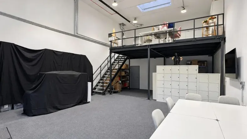 Geräumiger offener Arbeitsbereich mit hoher Decke, Teppichboden und einer modernen Galerieebene.