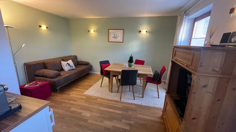 Gemütlicher Wohn-Essbereich mit Sofa, Esstisch und Holzmöbeln, ideal für entspannte Stunden.