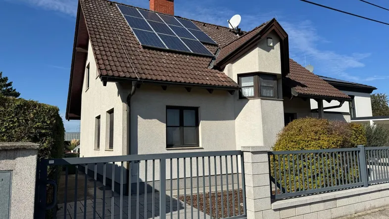 Einfamilienhaus mit Satteldach, Solaranlage und gepflegtem Vorgarten unter blauem Himmel.