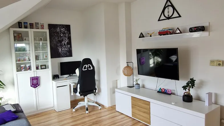 Helles Wohnzimmer mit Holzboden, Schreibtischbereich und gemütlicher Sitzecke unter der Dachschräge.