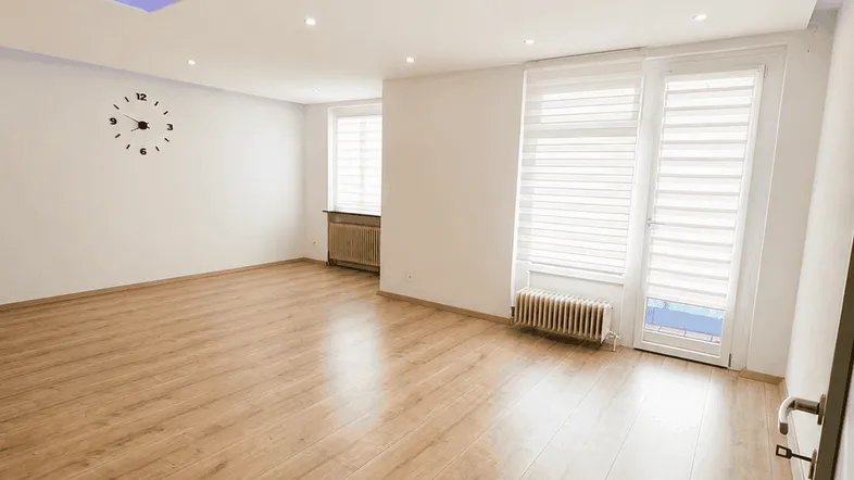 Helles Wohnzimmer mit modernem Lichtkonzept, Holzboden und Zugang zu einem Balkon.