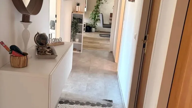 Heller Flur mit modernem Spiegel, schwebender Konsole und Teppichläufer auf Fliesenboden.