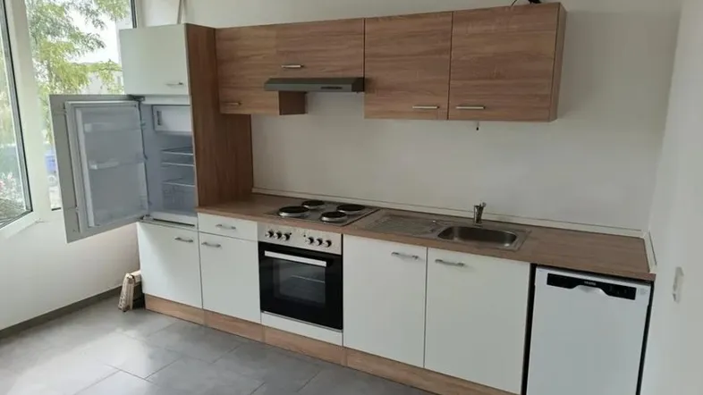 Helle Einbauküche mit Holz- und weißen Fronten, ausgestattet mit Kühlschrank, Herd und Geschirrspüler.