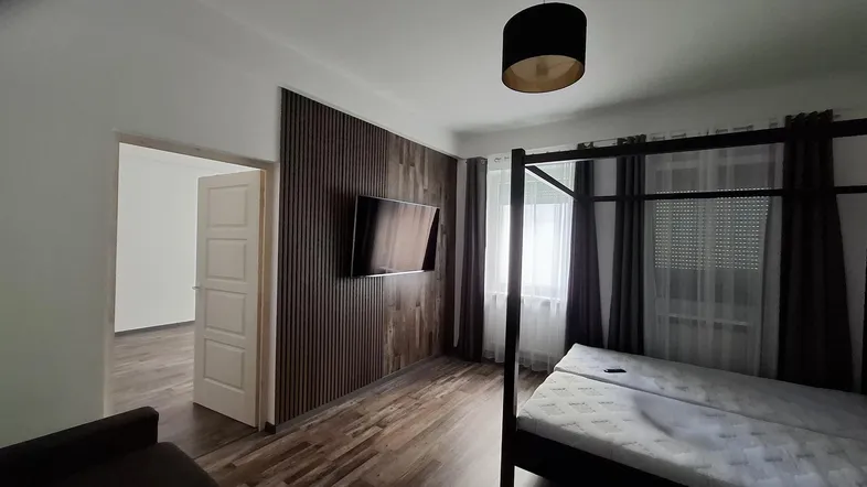 Geräumiges Schlafzimmer mit Holzwandverkleidung, Doppelbett und Blick nach draußen.