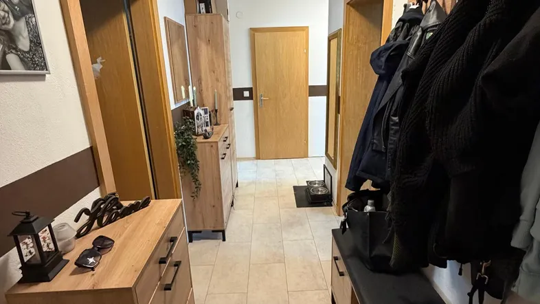 Heller Flur mit Holzmöbeln, Garderobe und gefliestem Boden, der einen einladenden Eingangsbereich schafft.