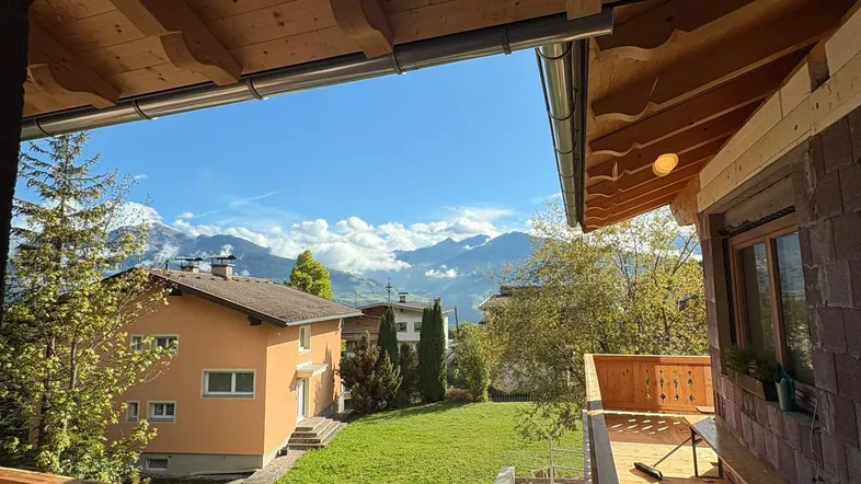 Geräumiger Holzbalkon mit traditionellem Dachüberstand und weitem Blick auf die umliegende Berglandschaft.