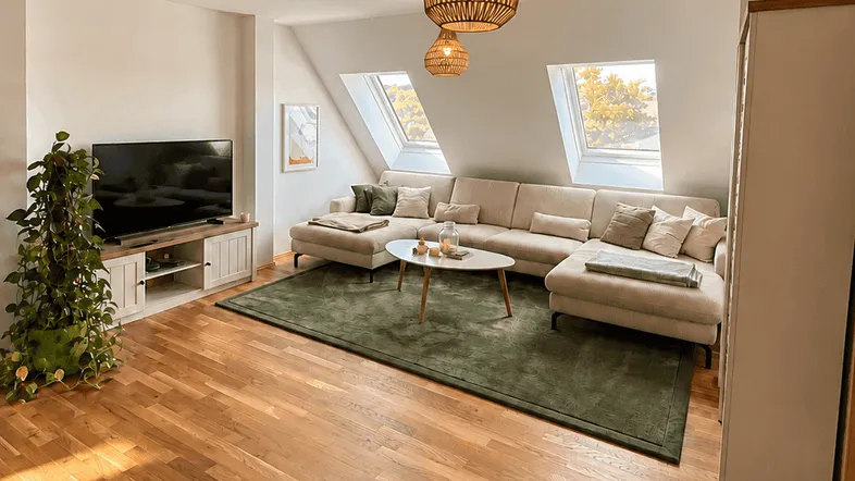 Helles Wohnzimmer mit gemütlichem Sofa, Holzboden und Dachfenstern, ideal für entspannte Stunden.