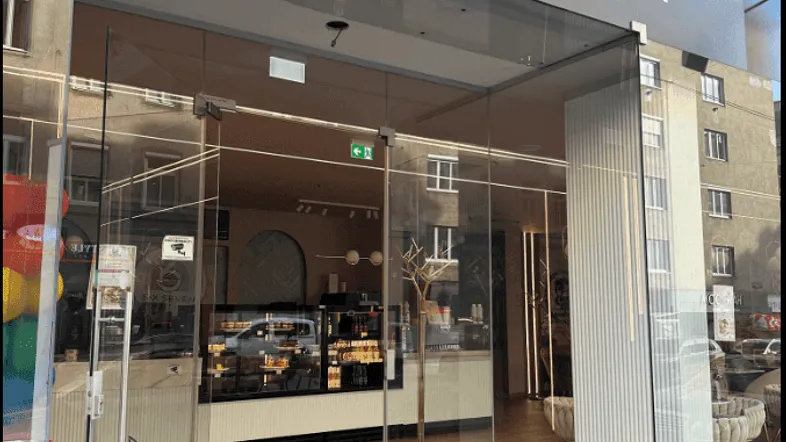 Eingangsbereich eines modernen Cafés mit großer Glasfassade und stilvollem Schriftzug.