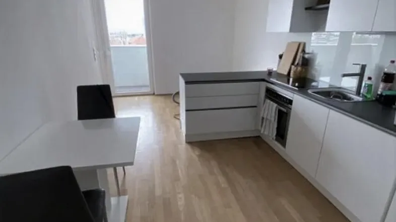 Helle, moderne Küche mit integriertem Essbereich, Holzfußboden und direktem Zugang zum Balkon.