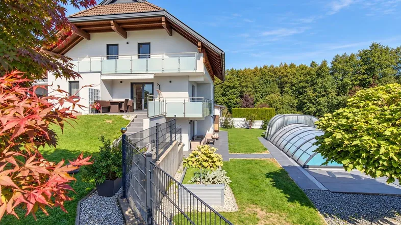 Modernes Haus mit großem Garten, überdachtem Pool und einer Terrasse mit Sitzgelegenheiten.