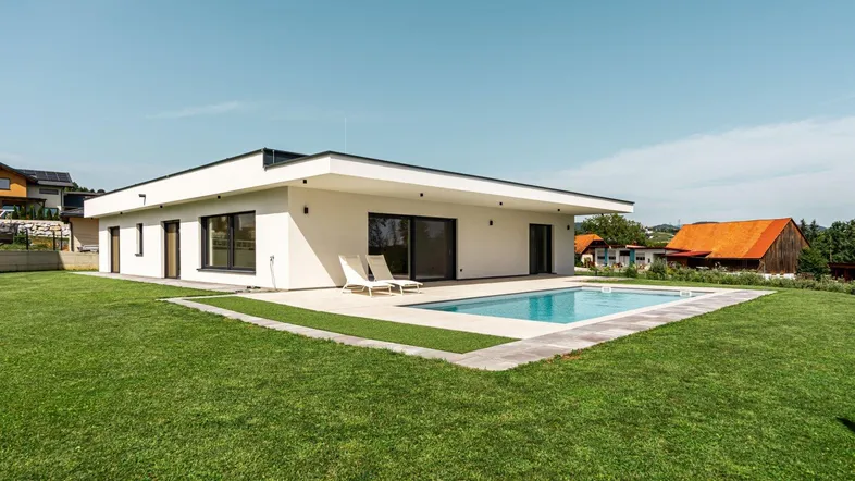 Modernes Einfamilienhaus mit Flachdach, großem Garten und privatem Swimmingpool in ländlicher Umgebung.