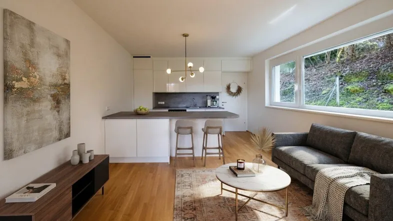 Helles, offenes Wohnzimmer mit integrierter Küche, Holzboden und modernen Möbeln.