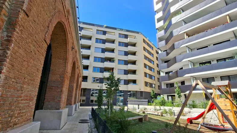 Moderne Wohngebäude und historische Backsteinarchitektur mit einem Spielplatz im Vordergrund.