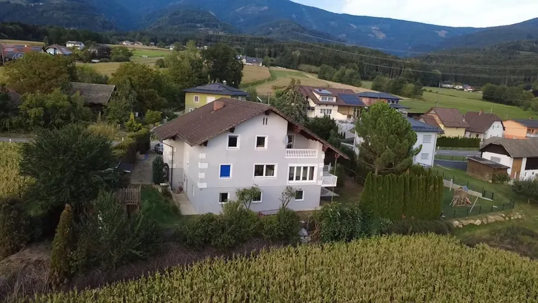 Luftaufnahme eines Einfamilienhauses mit Satteldach und umliegender grüner Landschaft.