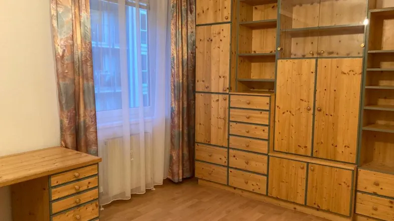 Geräumiges Zimmer mit Kiefernholzmöbeln, großem Fenster und hellem Parkettboden.