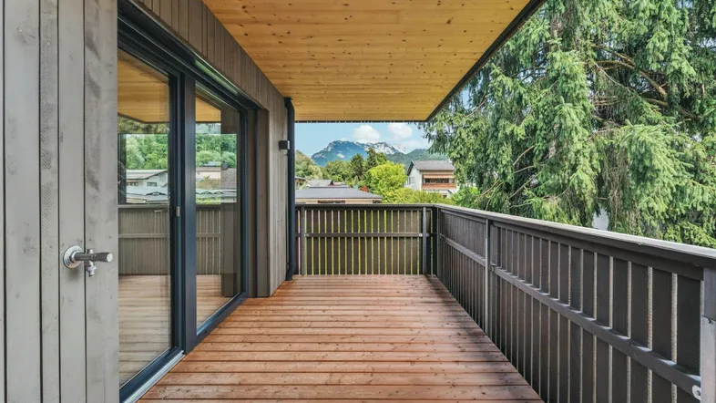 Geräumiger Balkon mit Holzboden, Holzdecke und Bergblick in moderner Architektur.