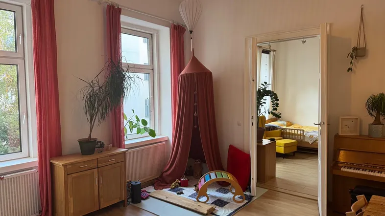 Helles Wohnzimmer mit Spielecke, Klavier und Zugang zu einem gemütlichen Schlafzimmer.