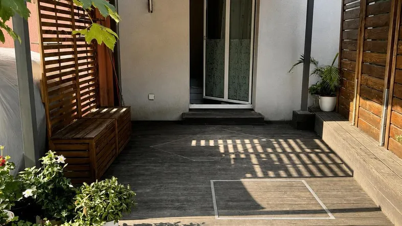 Geräumige Terrasse mit Holzboden, Sitzbänken und einer Markise, ideal für entspannte Stunden im Freien.