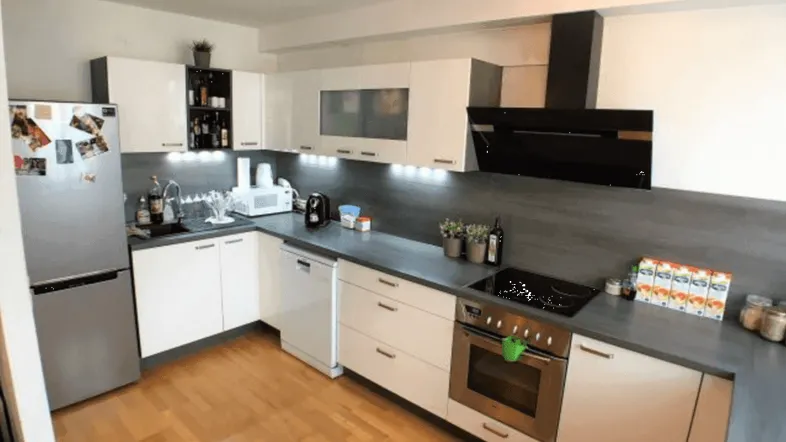 Moderne Küche mit weißen Schränken, Holzfußboden und integrierten Geräten für den täglichen Gebrauch.