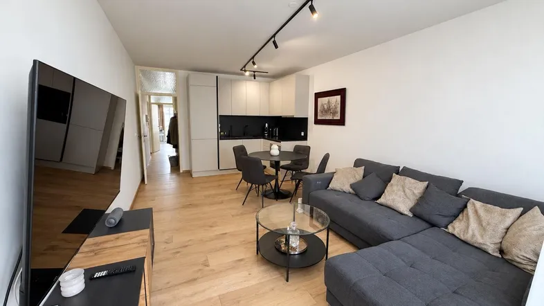 Heller offener Wohn- und Essbereich mit moderner Küche, Sofa und Holzboden.