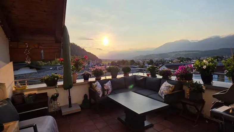 Große möblierte Dachterrasse mit atemberaubendem Sonnenuntergang und Panoramablick auf die Berge.