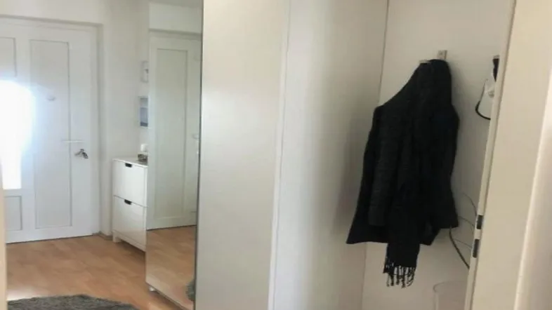 Heller Flur mit Spiegelschrank, Garderobe und Holzfußboden, der viel natürliches Licht erhält.