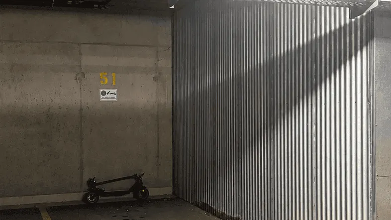 Tiefgaragenstellplatz mit E-Scooter, sichtbaren Leitungen und Wellblechwand in einer modernen Anlage.