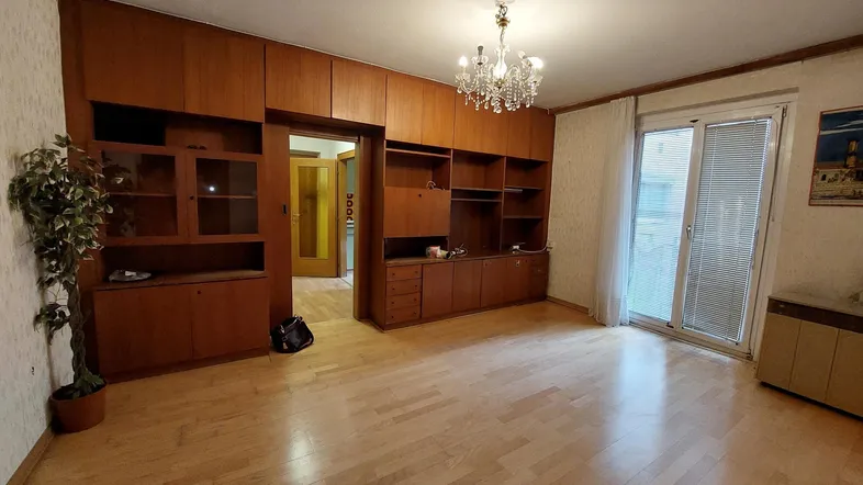 Geräumiges Wohnzimmer mit Parkettboden, Einbauschränken und Zugang zum Balkon.