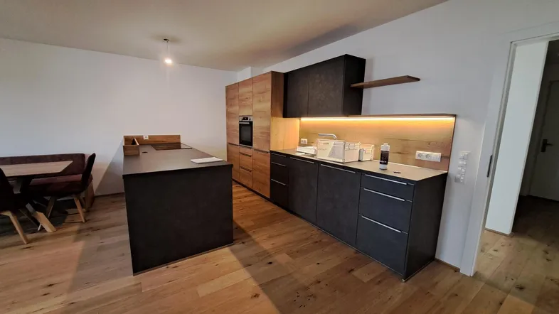 Moderne offene Küche mit Kücheninsel, Holzelementen und integriertem Essbereich.