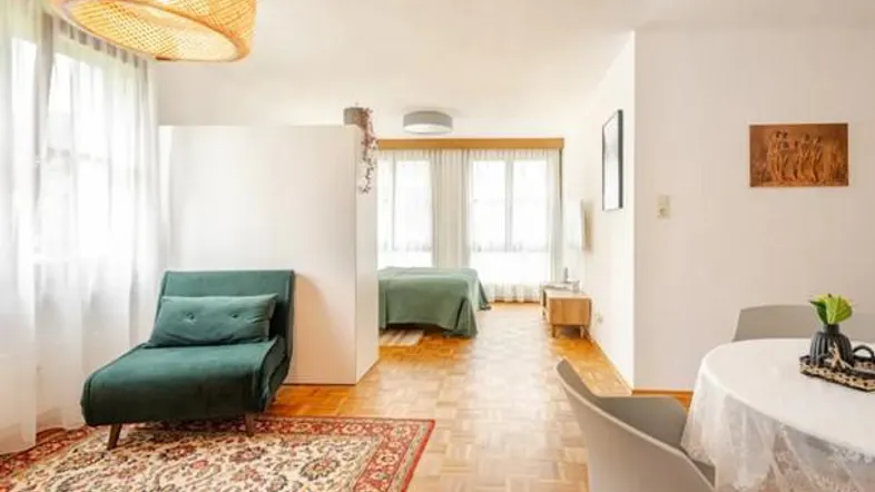 Heller, offener Wohnbereich mit Parkettboden, separatem Schlafbereich und Essplatz.