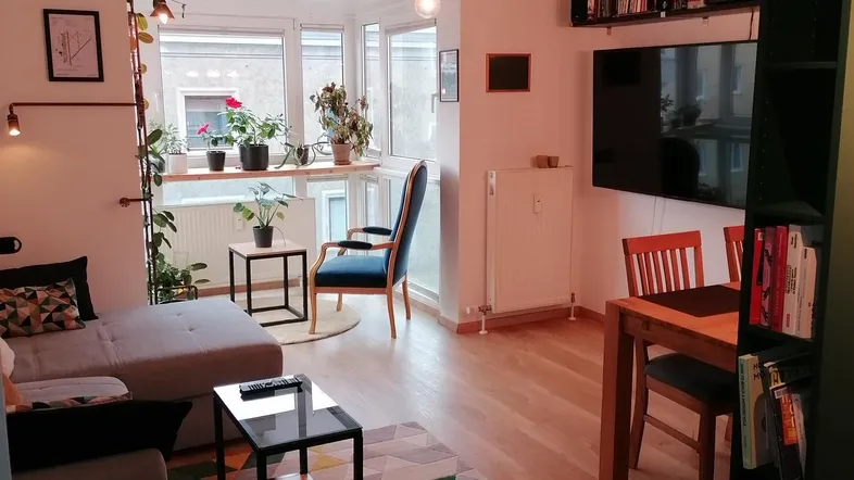 Gemütlicher Wohn-Essbereich mit Holzboden, Sofa, Esstisch und Blick auf die Umgebung.
