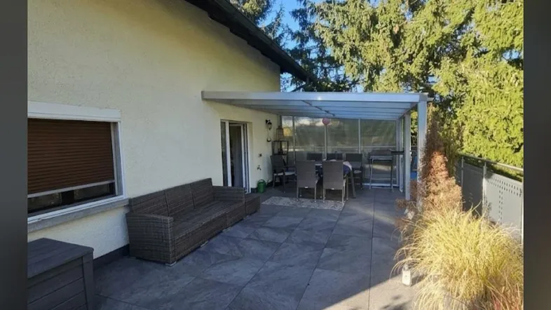 Geräumige Terrasse mit Überdachung, bequemen Sitzgelegenheiten und Blick ins Grüne.