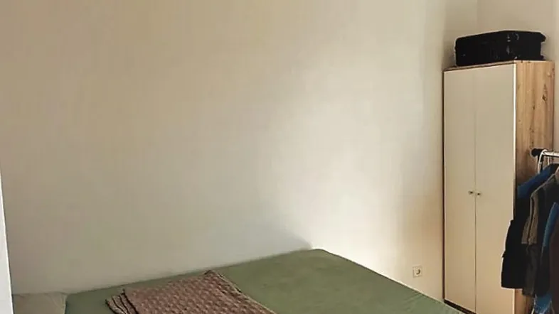 Helles Schlafzimmer mit Parkettboden, einem bequemen Bett und einem praktischen Kleiderschrank.