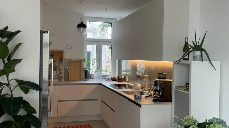 Moderne, offene Küche mit weißen Schränken, integrierten Geräten und Blick auf den Essbereich.