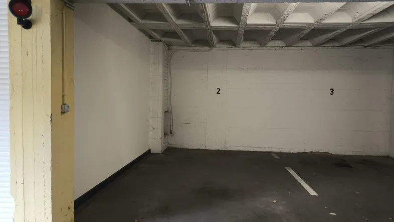 Geräumiger Tiefgaragenstellplatz mit Betonwänden und -decke, gut beleuchtet und funktional.