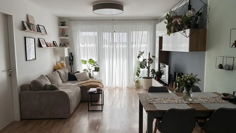 Helles Wohn- und Esszimmer mit Parkettboden, bequemer Couch und modernem Esstisch.