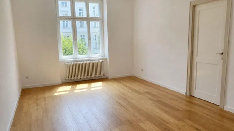 Heller Raum mit großen Fenstern, Parkettboden und Heizkörper, ideal als Wohn- oder Schlafzimmer.