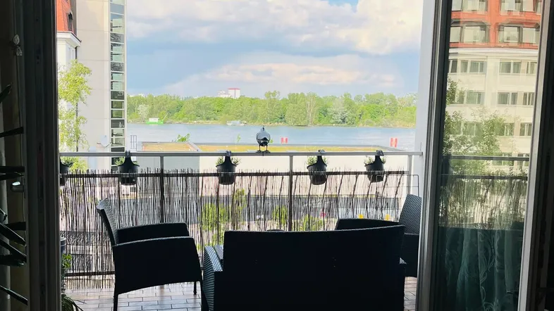 Heller Wohnbereich mit Zugang zum Balkon und weitem Blick auf den See und die umliegenden Gebäude.