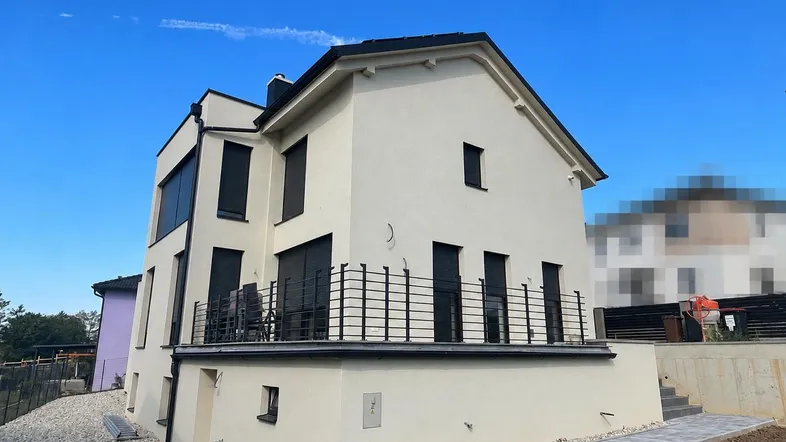 Modernes Einfamilienhaus mit heller Fassade, Balkon und gepflegtem Außenbereich.