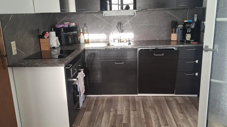 Moderne Küche mit dunklen und weißen Schränken, ausgestattet mit Spülmaschine und Induktionskochfeld.