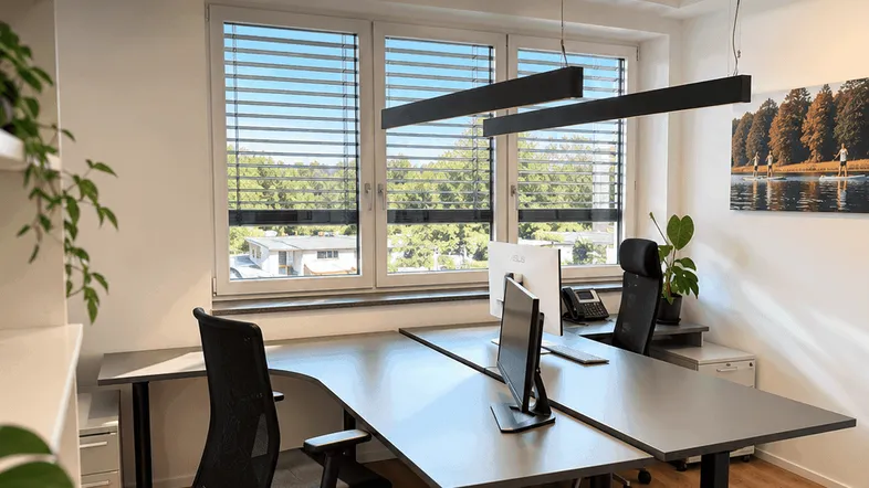 Modernes Büro mit flexiblen Arbeitsplätzen, großen Fenstern und Blick ins Grüne.