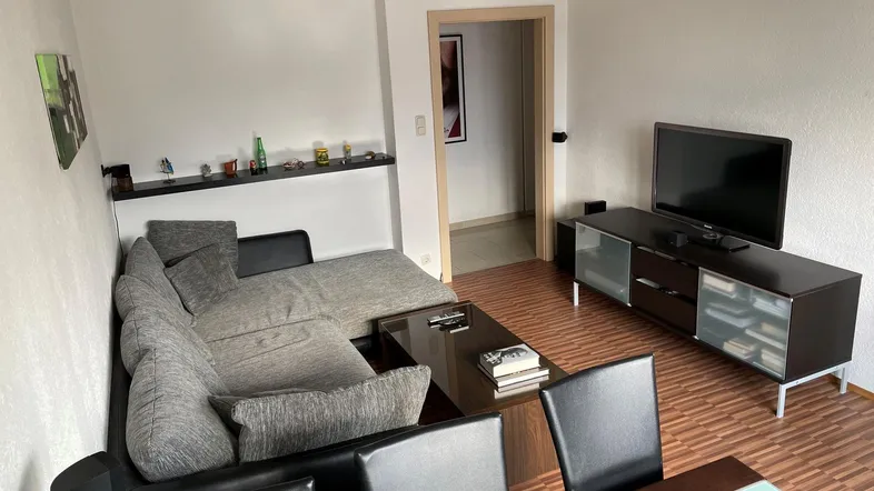 Gemütlicher Wohn- und Essbereich mit Ecksofa, Fernseher und Esstisch, ideal für gesellige Abende.