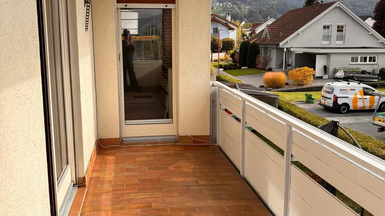 Geräumiger Balkon mit Fliesenboden und Blick auf die umliegende Wohngegend und Berge.