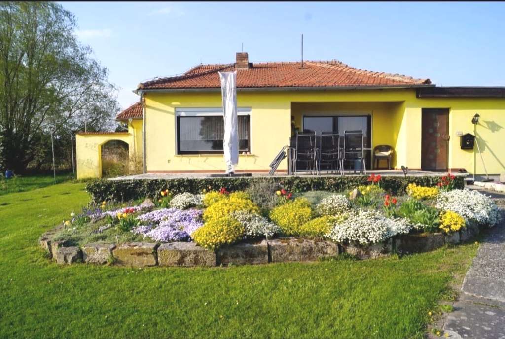Immobilie in Hofheim in Unterfranken - Wohnen in absoluter Naturnähe! Walmdachbungalow mit Südterrasse, Nebengebäude, Carport auf einem  - Bild 1