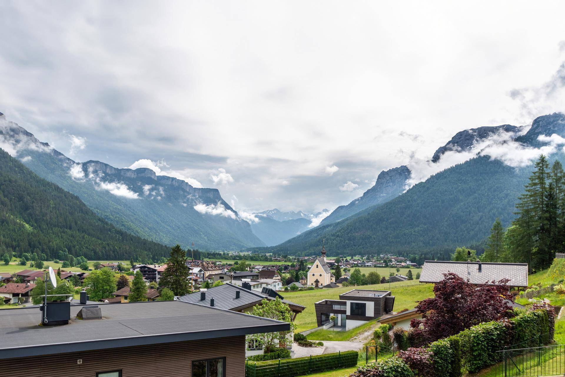 Panoramablick auf ein malerisches Alpendorf mit grünen Wiesen und majestätischen Bergen.