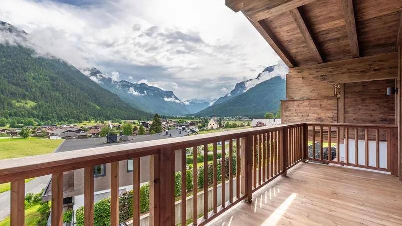 Geräumiger Holzbalkon mit atemberaubendem Bergblick und Blick auf das Tal.