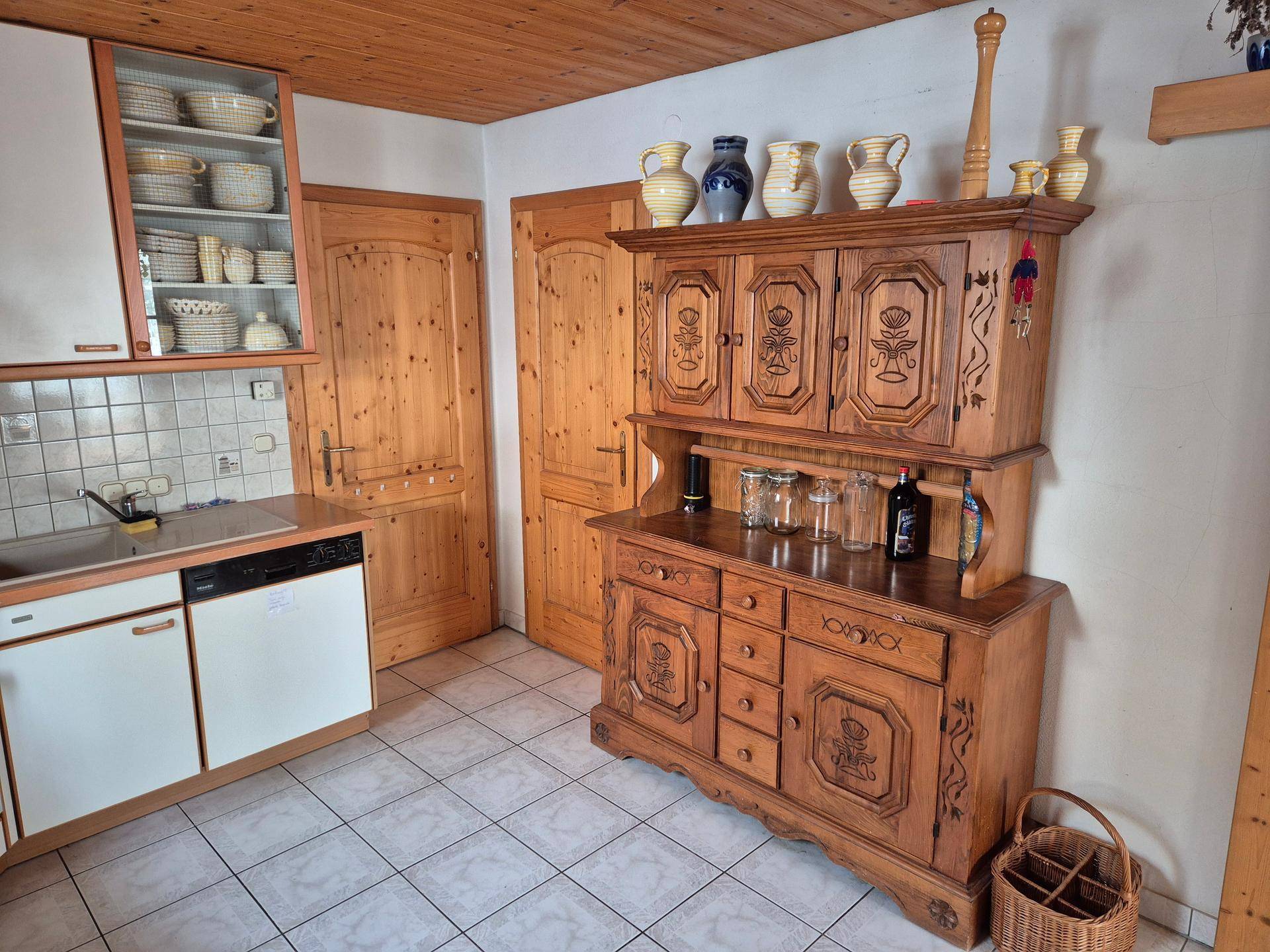 Landhausküche mit traditionellem Holzschrank, Fliesenboden und Holztüren.